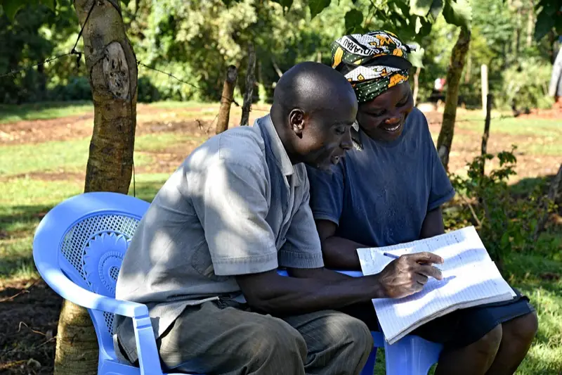 Deux personnes au Kenya travaillent ensemble sur les notes d’un cahier de formation